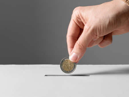 close up of hand putting coin into donation box