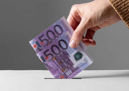 close up of hand putting money into donation box