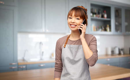 happy woman in apron calling on smartphone