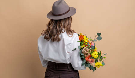 woman in hat holding bunch of flowersの写真素材