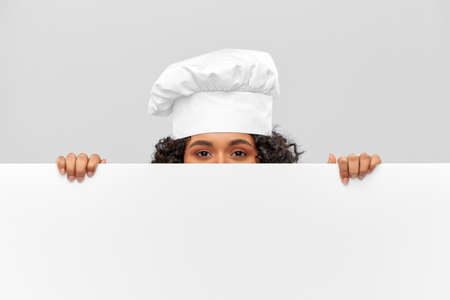 female chef hiding behind white boardの写真素材