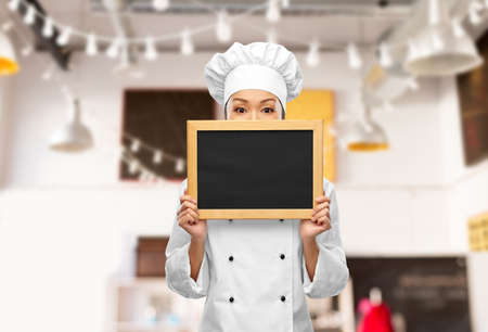 female chef holding black chalkboardの写真素材