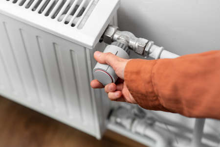 close up of hand turning radiator toggle at home
