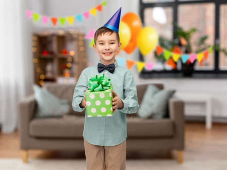 smiling boy in party hat with birthday gift