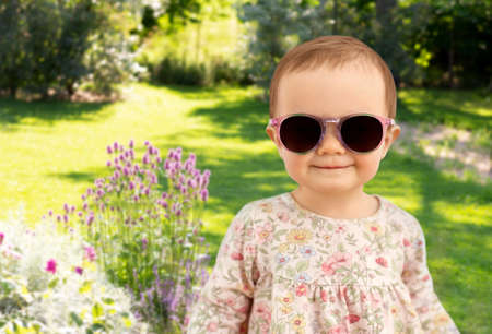 happy little baby girl in sunglasses over gardenの写真素材