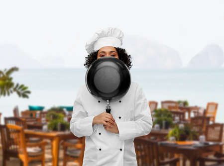 female chef peeking out from behind frying panの写真素材
