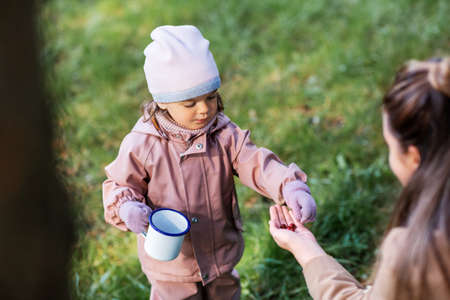 mother with baby daughter picking berries in park