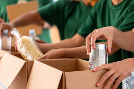 close up of volunteers packing food in boxes