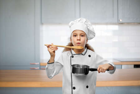 girl in chefs toque with spoon and saucepanの写真素材
