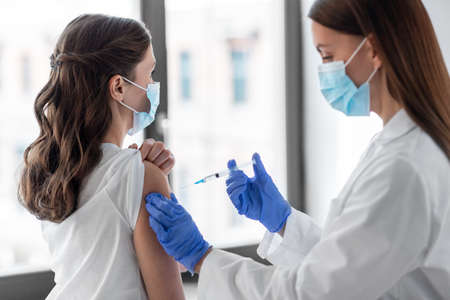 female doctor with syringe vaccinating patient