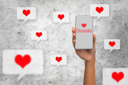 close up of hand with donate icon on smartphoneの写真素材