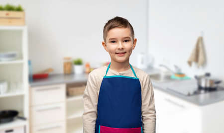 smiling little boy in apron in kitchenの写真素材