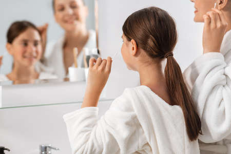 mother and daughter cleaning ears with cotton swabの写真素材