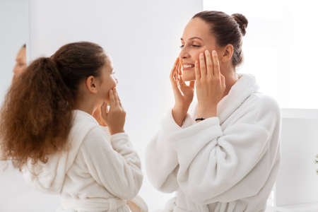 mother and daughter touching faces in bathroomの写真素材
