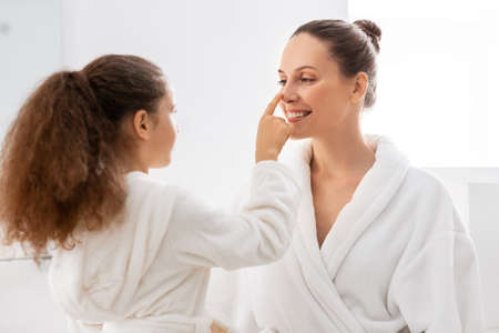 happy smiling mother and daughter at bathroomの写真素材