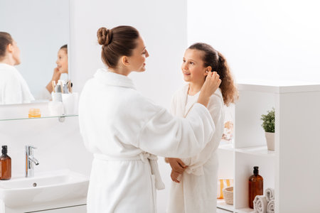 happy mother cleaning daughters ear in bathroomの写真素材
