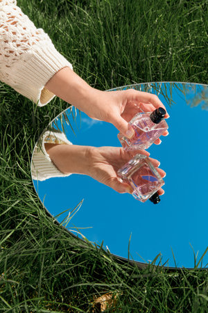 hand with perfume and sky reflection in mirror