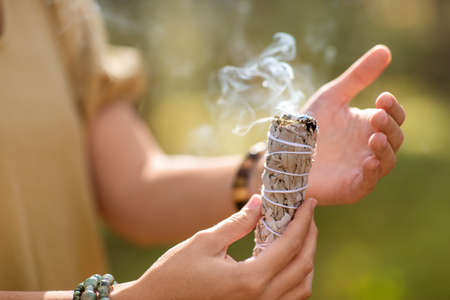 woman with sage performing magic ritual in forestの写真素材