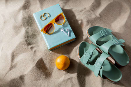 slippers, orange, earbuds and sunglasses on beach