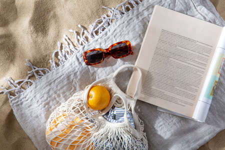 bag of oranges, sunglasses and magazine on beachの写真素材