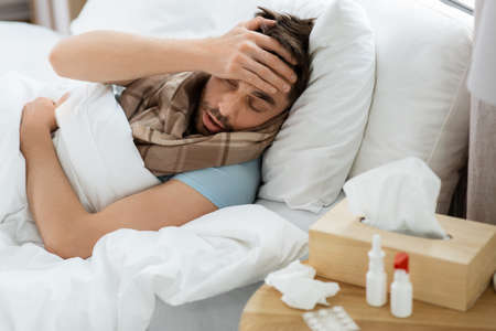 sick man having headache lying in bed at homeの写真素材