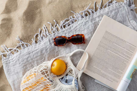 bag of oranges, sunglasses and magazine on beachの写真素材