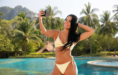 woman in bikini taking selfie over swimming poolの写真素材