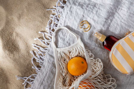 bag of oranges and sunscreen oil on beach blanket