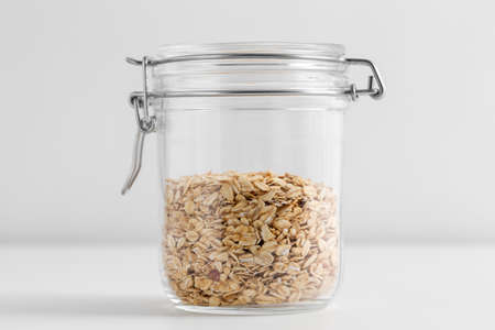 close up of jar with oat flakes on white