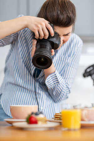 food photographer with camera working in kitchenの写真素材