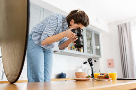 food photographer with camera working in kitchenの写真素材