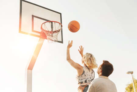 happy couple playing on basketball on playground