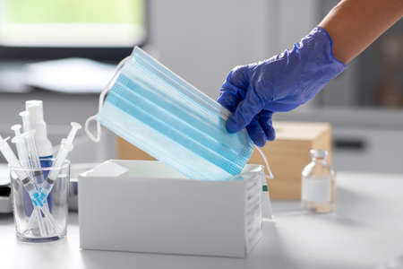 close up of hand in glove taking medical mask