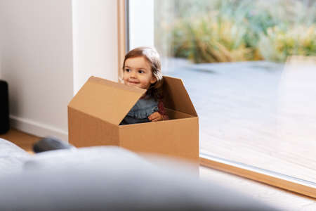 little baby girl sitting in cardboard box at home