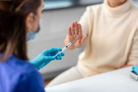 nurse with syringe and woman refusing from vaccine