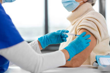 nurse with syringe making injection to woman