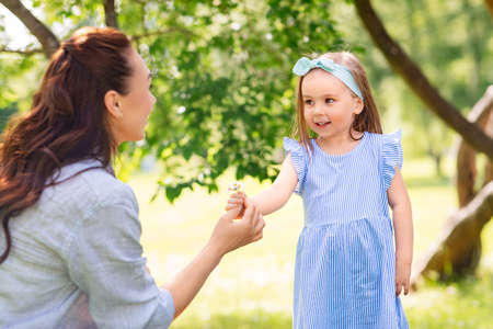 happy mother and daughter with flowers at park