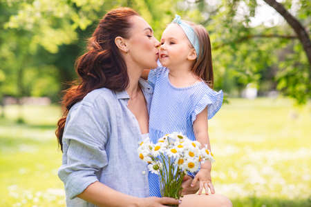 happy mother and daughter with chamomiles at park