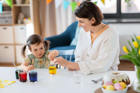 mother with child dyeing easter eggs at homeの写真素材