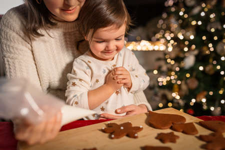 mother and daughter decorating gingerbread at homeの写真素材