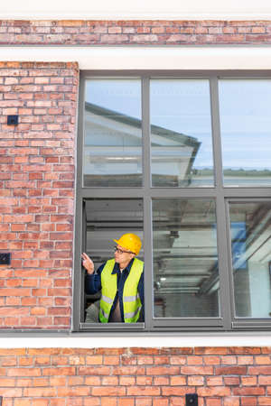 male builder in helmet looking out window
