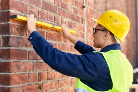 male builder with level measuring wall