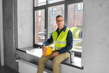 happy builder with tumbler sitting on window sill