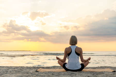 woman meditating in lotus pose on beachの写真素材
