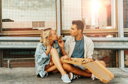 happy couple eating pizza on city roof top parkingの写真素材
