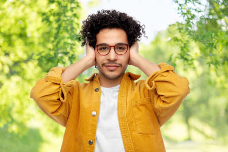 man closing ears by hands on natural background