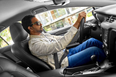 indian man or driver in sunglasses driving car