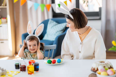 mother with child dyeing easter eggs at home