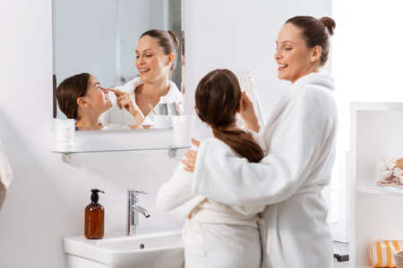 mother and daughter in front of mirror at bathroomの写真素材