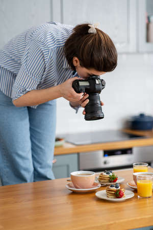 food photographer with camera working in kitchenの写真素材